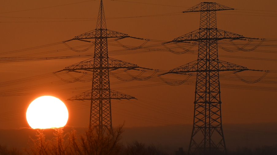 Die Sonne geht hinter Strommasten auf. / Foto: Martin Schutt/dpa