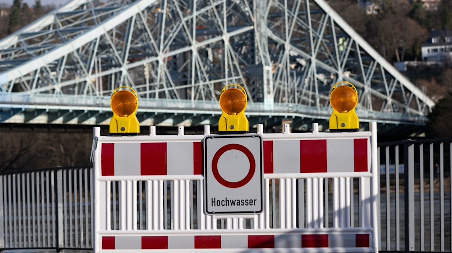 Ein Schild an einer Absperrung warnt vor Hochwasser. / Foto: Robert Michael/dpa