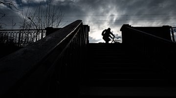 Ein Radfahrer fährt am Vormittag bei Wind und dunklen Wolken über die Marienbrücke. / Foto: Robert Michael/dpa