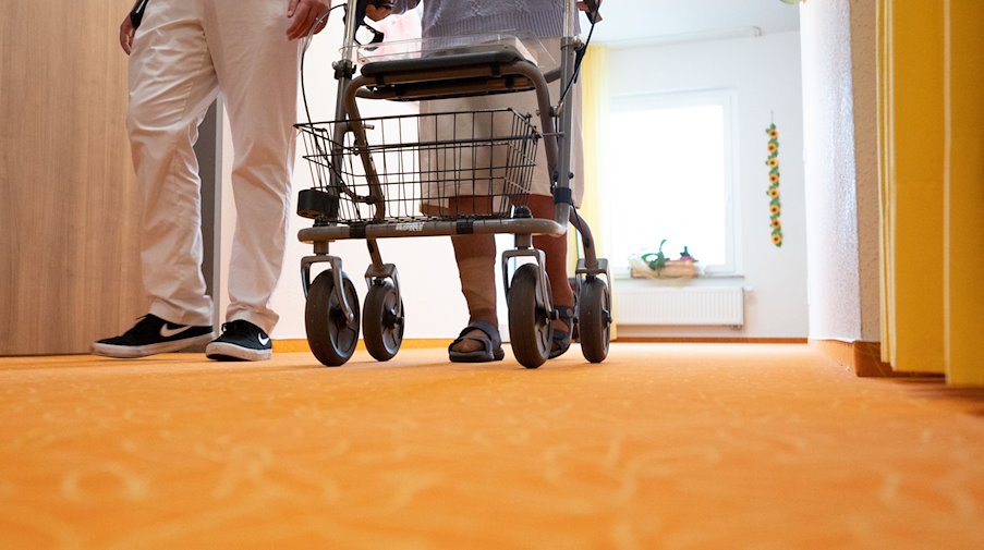 A caregiver walks down the corridor with a resident in a nursing home / Photo: Bernd Weißbrod/dpa/Symbolic image