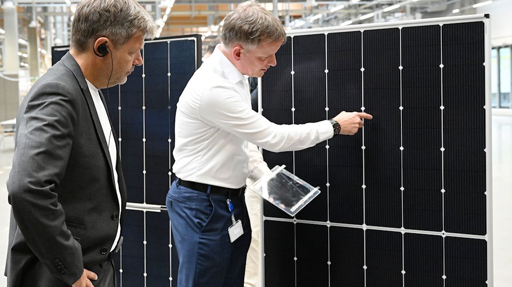 جونتر إيرفورت (r)، الرئيس التنفيذي لشركة ماير بوركر تكنولوجي أ: جي، يشرح لوزير الاقتصاد الاتحادي روبرت هابيك خلال زيارة للشركة الألواح الشمسية. / صورة: سورين ستاشي / دبا