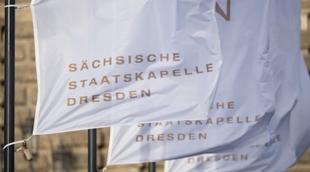 Banderas con la inscripción "Sächsische Staatskapelle Dresden" ondeando al viento frente a la Semperoper / Foto: Robert Michael/dpa