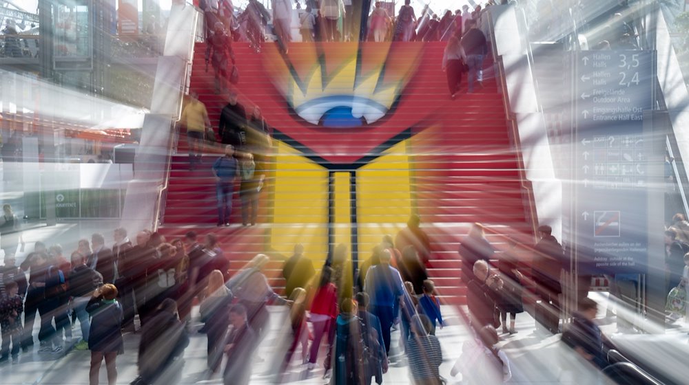 الزوار يمرون فوق سلم يحمل شعار معرض لايبزيغ للكتاب. / صورة: هندريك شميت / شركة الأخبار الألمانية