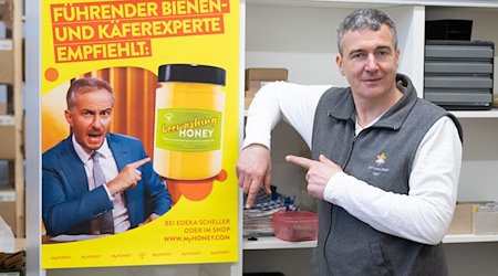 Rico Heinzig, Imker, steht neben einem Plakat mit dem Foto des Moderators Jan Böhmermann. / Foto: Sebastian Kahnert/dpa