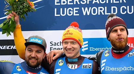 El alemán Max Langenhan (M), ganador, sube al podio tras la carrera entre el austriaco David Gleirscher (izq.), segundo, y el letón Krsiters Aparjods, tercero / Foto: Robert Michael/dpa