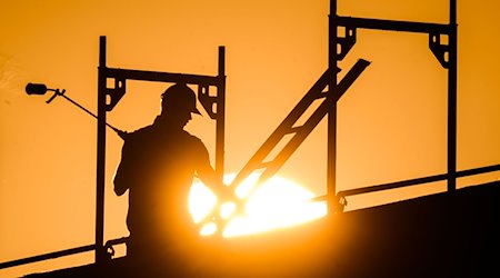 Ein Bauarbeiter steht mit einem Gasbrenner beim Bau eines Mehrfamilienhauses im Neubaugebiet. / Foto: Julian Stratenschulte/dpa