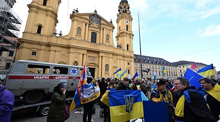 Protesters stand with Ukrainian flags in front of a shot-up ambulance at a demonstration during the security conference on Odeonsplatz. More than 160,000 war refugees from Ukraine are currently living in Bavaria / Photo: Felix Hörhager/dpa