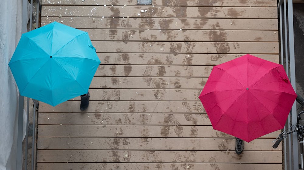 Passanten gehen unter Regenschirmen in Dresden spazieren. / Foto: Sebastian Kahnert/dpa