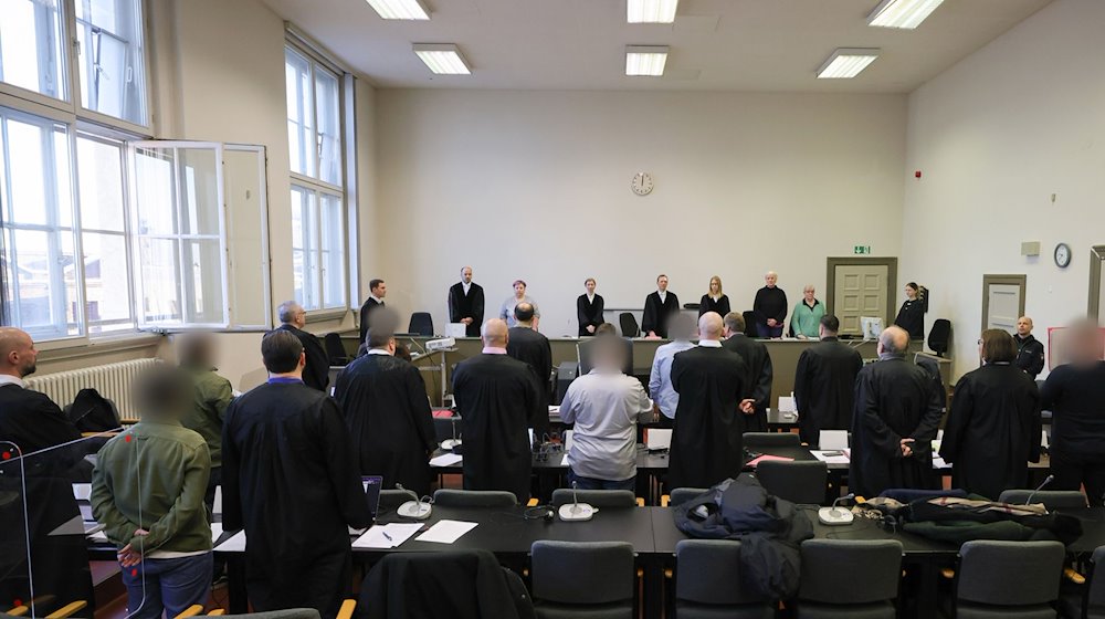 Die Angeklagten und ihre Anwälte stehen im Gerichtssaal. / Foto: Christian Charisius/dpa