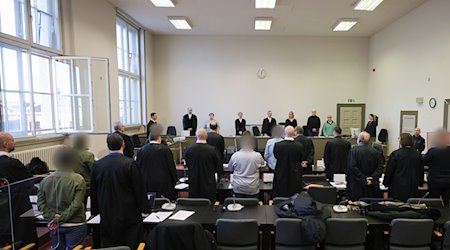 Die Angeklagten und ihre Anwälte stehen im Gerichtssaal. / Foto: Christian Charisius/dpa