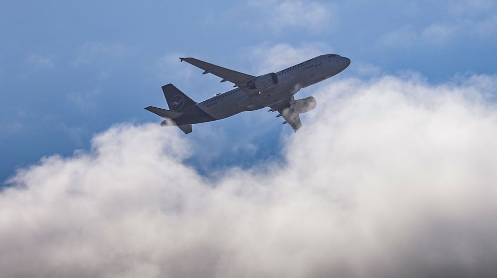 Ein Flugzeug der Lufthansa fliegt über den Wolken am Himmel über Dresden. / Foto: Robert Michael/dpa/Symbolbild