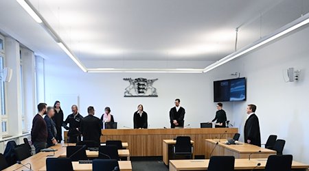 Richter, Anwälte, der Angeklagte (2.v.l) und der Dolmetscher stehen in einem Prozess im Gerichtssaal. / Foto: Bernd Weißbrod/dpa