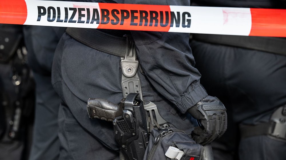 Polizisten stehen hinter einem Polizei-Flatterband. / Foto: Hannes P. Albert/dpa/Symbolbild