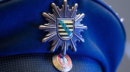 Das Wappen der sächsischen Polizei ist an der Mütze eines Polizisten angebracht. / Foto: Robert Michael/dpa