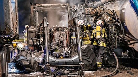Feuerwehrleute stehen zwischen verbrannten landwirtschaftlichen Geräten. / Foto: Andre März/ErzgebirgsNews/dpa
