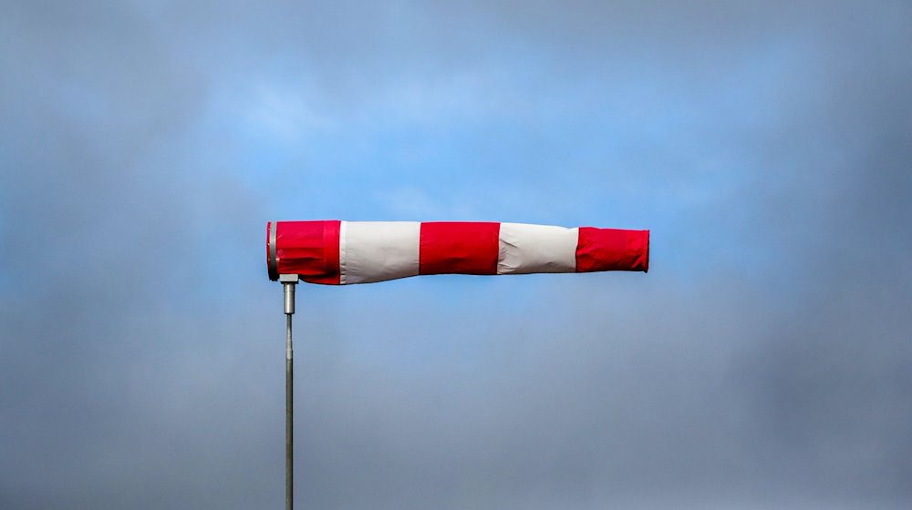 Hinter einem im Sturm stehenden Windsack hat sich eine Wolkenlücke gebildet. / Foto: Thomas Warnack/dpa