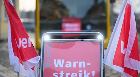 Ein Schild mit der Aufschrift «Warnstreik» steht vor einem Bus der Dresdner Verkehrsbetriebe. / Foto: Robert Michael/dpa