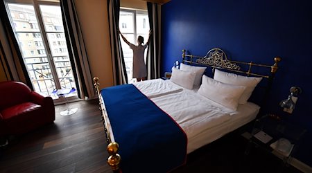 A service employee opens the curtains in a hotel room in the private, owner-managed Berlin boutique and design hotel THE DUDE / Photo: Jens Kalaene/dpa-Zentralbild/dpa