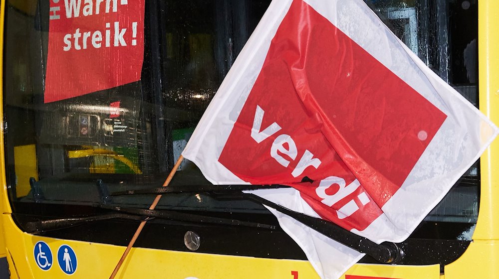 Ein Bus mit einer Verdi-Fahne steht hinter einer Schranke an der Einfahrt zum Betriebshof der Berliner Verkehrsbetriebe (BVG) in Lichtenberg. / Foto: Annette Riedl/dpa