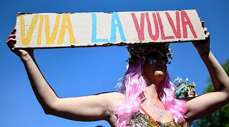 Eine Teilnehmerin hält bei der Parade zum Christopher Street Day (CSD) in der Innenstadt ein Plakat mit der Aufschrift "Viva La Vulva" in den Händen. / Foto: Patrick Seeger/dpa/Archivbild