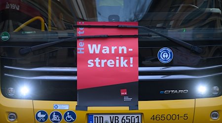 Ein Plakat «Warnstreik» ist an einem Bus der DVB im Betriebshof Trachenberge unter den Scheibenwischer geklemmt. / Foto: Robert Michael/dpa
