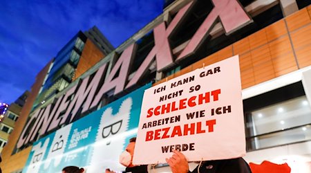 Kinobeschäftigte demonstrieren während der Filmfestspiele vor dem Cinemaxx-Kino mit Schildern und Transparenten für bessere Arbeitsbedingungen. / Foto: Gerald Matzka/dpa-Zentralbild/dpa