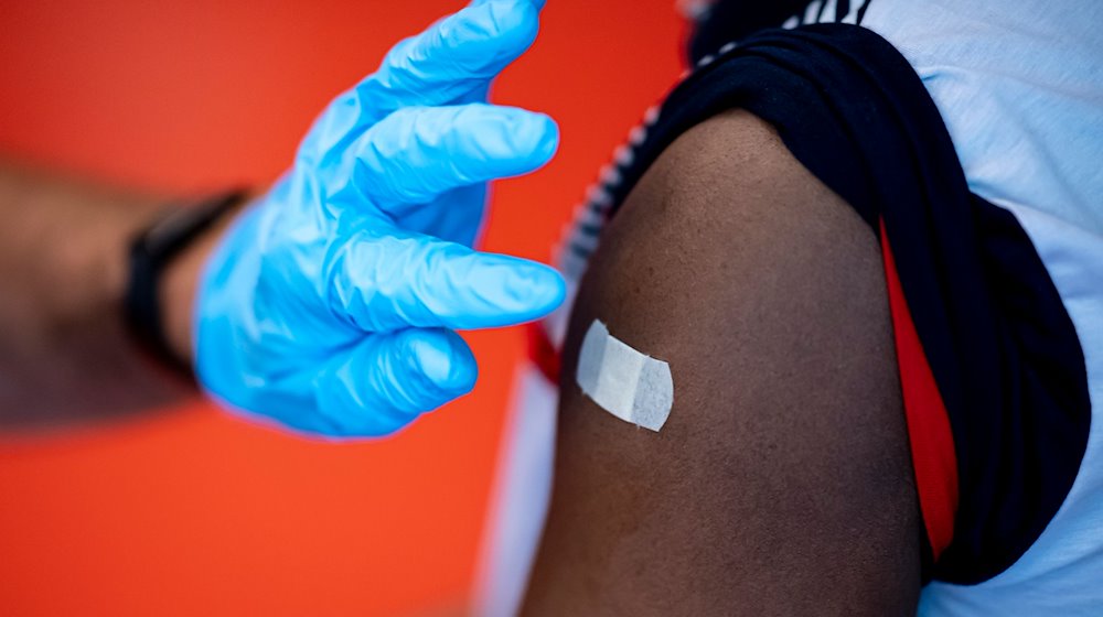 Un médico aplica un esparadrapo en la parte superior del brazo de una mujer tras la vacunación / Foto: Fabian Sommer/dpa/Imagen simbólica