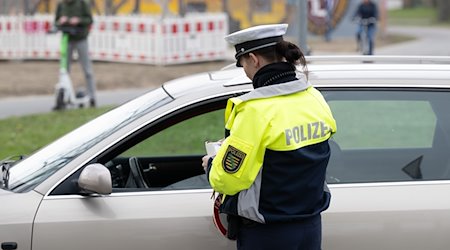 Eine Polizeiobermeisterin steht während einer Verkehrskontrolle am Georgplatz an einem Fahrzeug. / Foto: Sebastian Kahnert/dpa