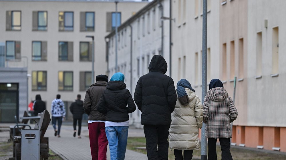 Migrantes caminan por el recinto de un centro de primera acogida para solicitantes de asilo / Foto: Patrick Pleul/dpa/Imagen simbólica