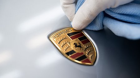Співробітник Porsche AG чистить герб Porsche на капоті на головному заводі в Цуффенгаузені / Фото: Marijan Murat/dpa