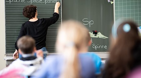 Вчителька пише на дошці в початковій школі слова, що починаються на "Sp". / Фото: Sebastian Gollnow/dpa