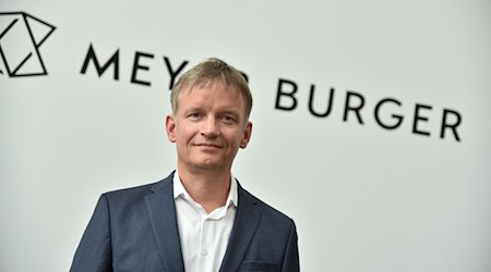 Der Geschäftsführer des Solarunternehmens Meyer Burger, Gunter Erfurt, steht vor einem Schriftzug mit dem Unternehmensnamen. / Foto: Simon Kremer/dpa