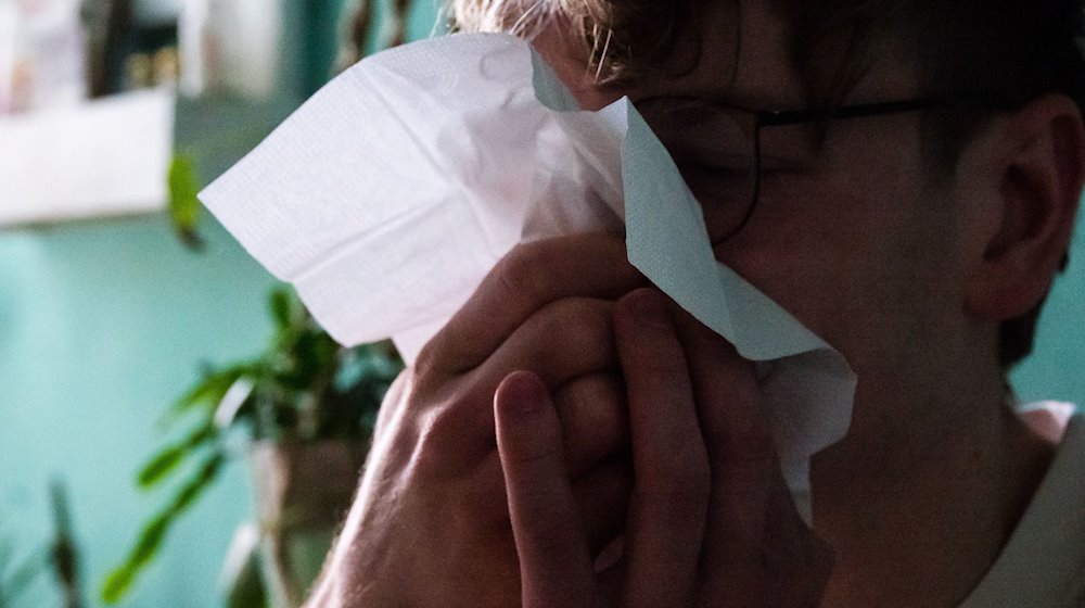 Ein Mann putzt sich mit einem Taschentuch die Nase. / Foto: Philip Dulian/dpa