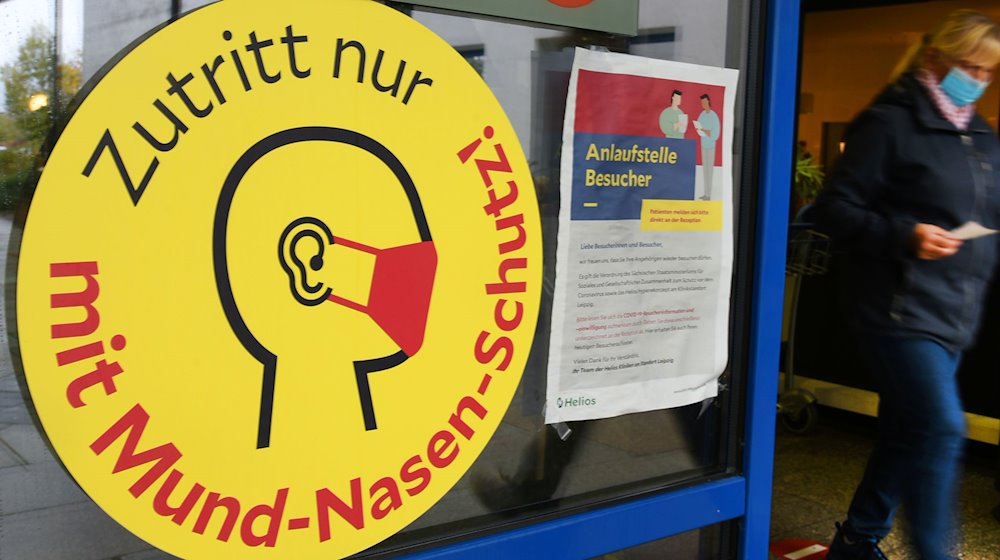 Ein großes Schild weist neben einem Eingang zu einer Klinik in Leipzig auf die Maskenpflicht hin. / Foto: Waltraud Grubitzsch/dpa