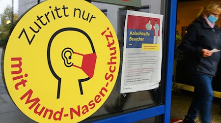 Ein großes Schild weist neben einem Eingang zu einer Klinik in Leipzig auf die Maskenpflicht hin. / Foto: Waltraud Grubitzsch/dpa
