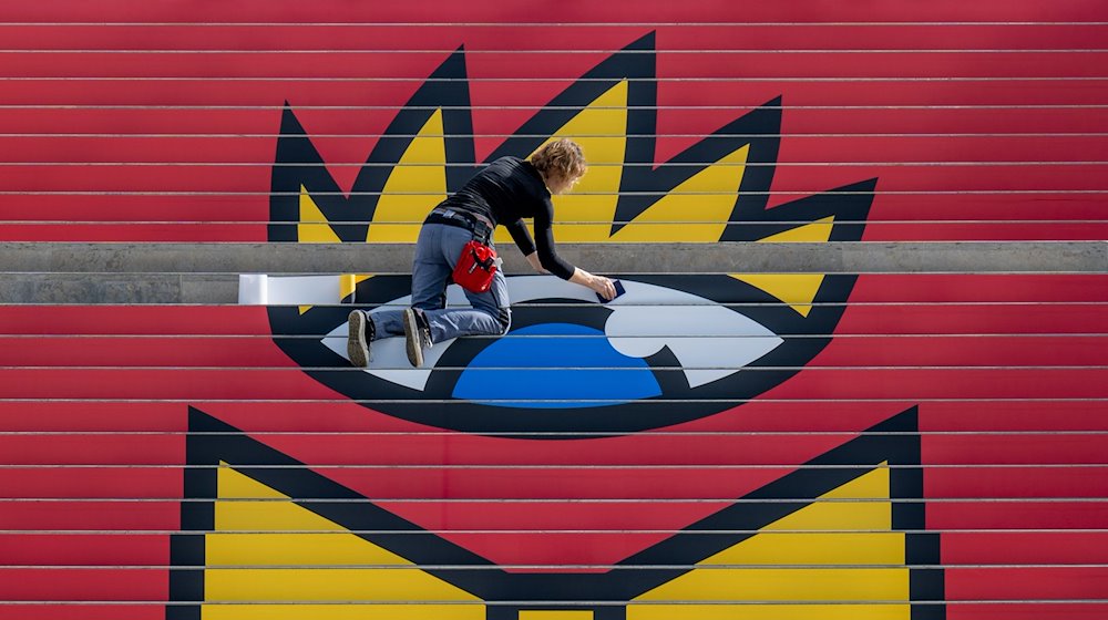 Jana Kielczynski from ZWA Design pastes the Book Fair logo on the 36 steps of a staircase in the Glass Hall at Messe Leipzig. / Photo: Hendrik Schmidt/dpa