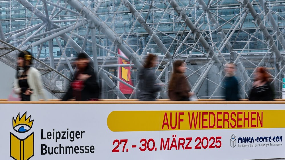 Besucher gehen auf der Leipziger Buchmesse an einem Schild „Auf Wiedersehen“ entlang. / Foto: Jan Woitas/dpa
