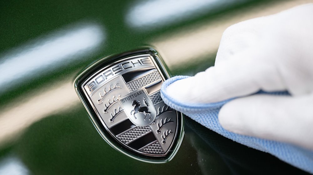 موظف في بورش أي جي ينظف شعار بورش على غطاء المحرك لسيارة بورش تايكان الكهربائية الكاملة بعد تركيبه. / الصورة: ماريان مورات / دب