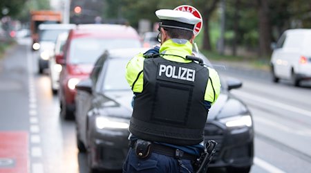 Ein Polizist der Polizeidirektion Dresden steht während einer Kontrolle mit einer Winkerkelle vor mehreren Fahrzeugen. / Foto: Sebastian Kahnert/dpa-Zentralbild/dpa