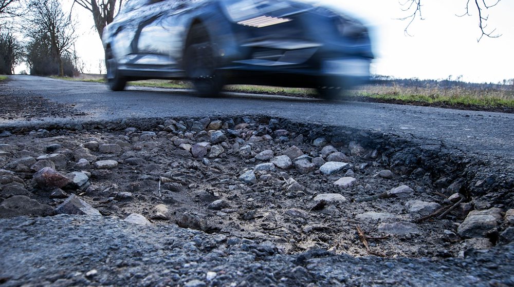 A car drives past a pothole. / Photo: Jens Büttner/dpa-Zentralbild/dpa/Symbolic image