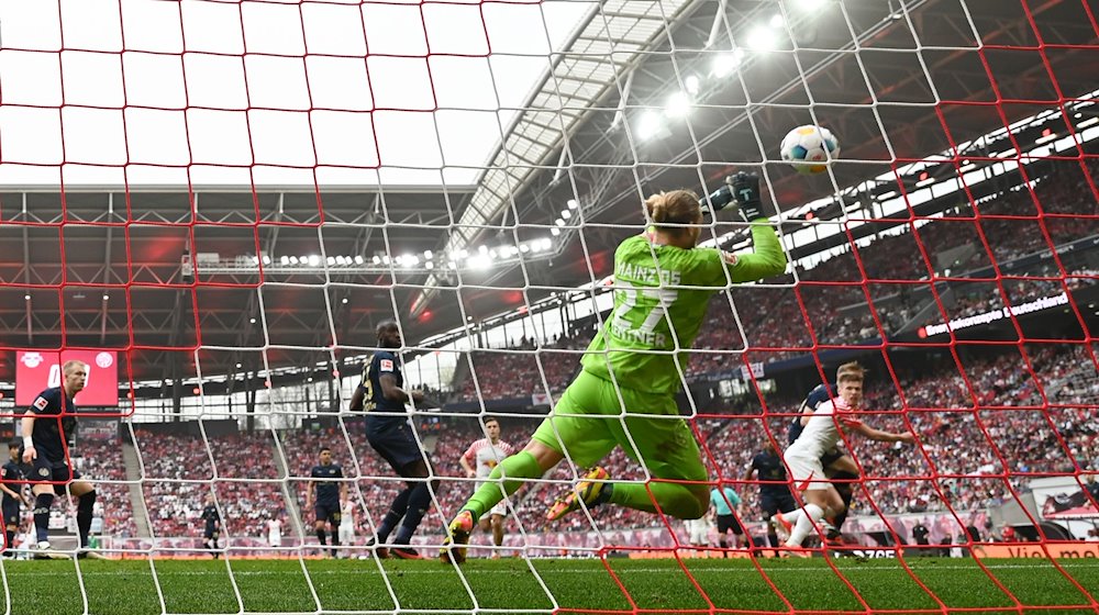 Mainz goalkeeper Robin Zentner (front) defends a ball from Leipzig's Dani Olmo (r). / Photo: Hendrik Schmidt/dpa