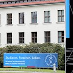 "Glück auf" steht auf einem Schild der Technischen Universität Bergakademie Freiberg am vor dem Karl-Kegel-Bau in Freiberg (Sachsen). / Foto: Jan Woitas/dpa/Archivbild