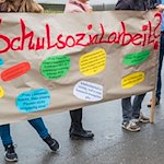 Teilnehmer halten ein Plakat mit der Aufschrift «Schulsozialarbeit» hoch. / Foto: Jens Büttner/dpa-Zentralbild/dpa/Archiv