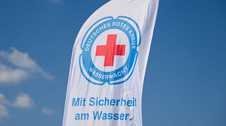 Eine Fahne der Wasserwacht weht am Bärwalder See im Wind. / Foto: Robert Michael/dpa