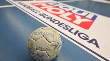 A handball lies on the floor with the Handball Bundesliga (HBL) logo behind it. / Photo: David Inderlied/dpa