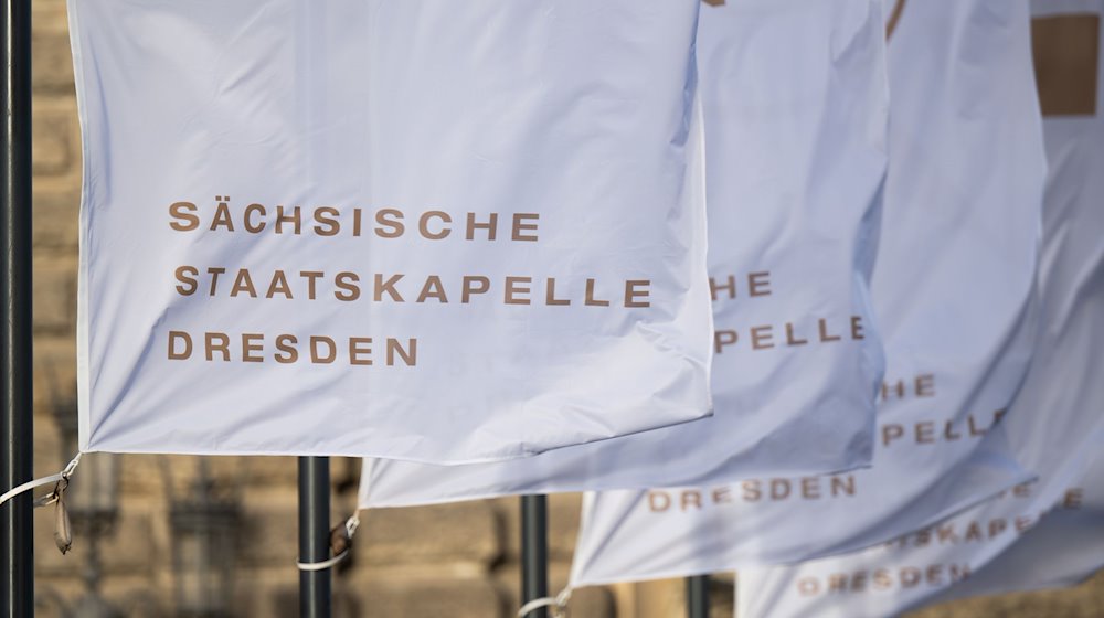 Flags with the inscription "Sächsische Staatskapelle Dresden" wave in the wind in front of the Semperoper / Photo: Robert Michael/dpa