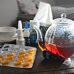 Medikamente und eine Kanne und Tasse Tee sind auf einem Nachttisch aufgestellt. / Foto: Bernd Weißbrod/dpa/Symbolbild