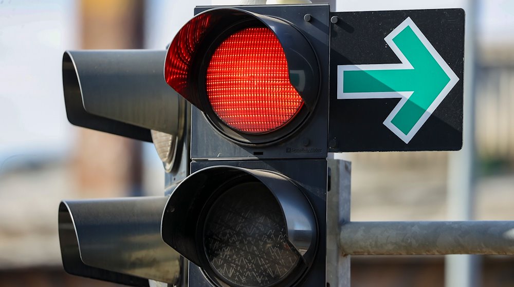 Ein Grüner Pfeil hängt neben einer roten Ampel an einer Kreuzung und erlaubt das Abbiegen trotz Rotlicht. / Foto: Jan Woitas/dpa-Zentralbild/dpa/Archivbild
