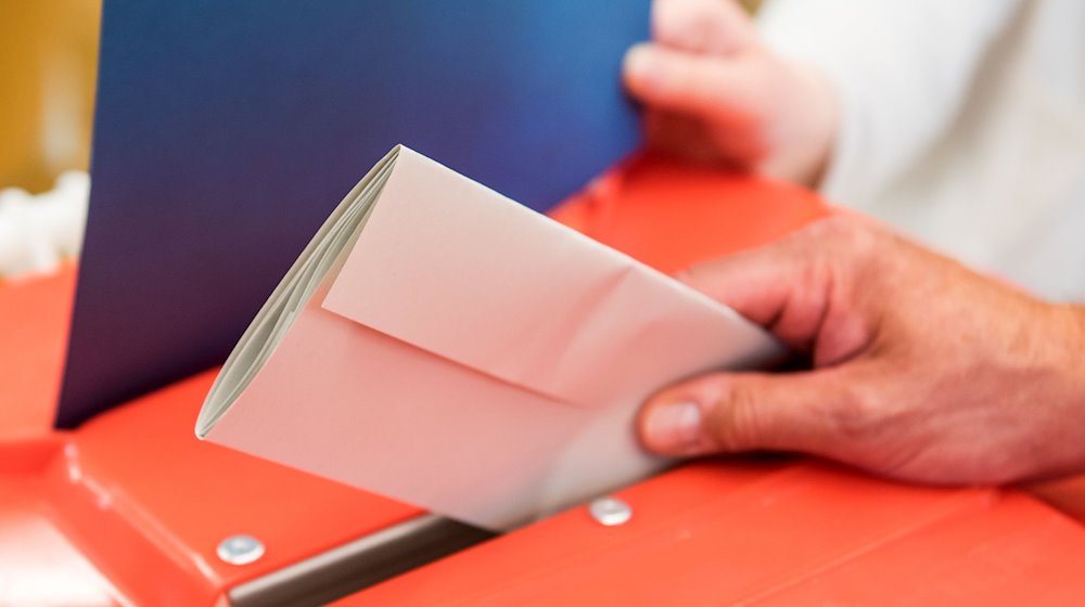 Un trabajador electoral deposita la papeleta de un votante en una urna de un colegio electoral / Foto: Daniel Bockwoldt/dpa/Archivbild