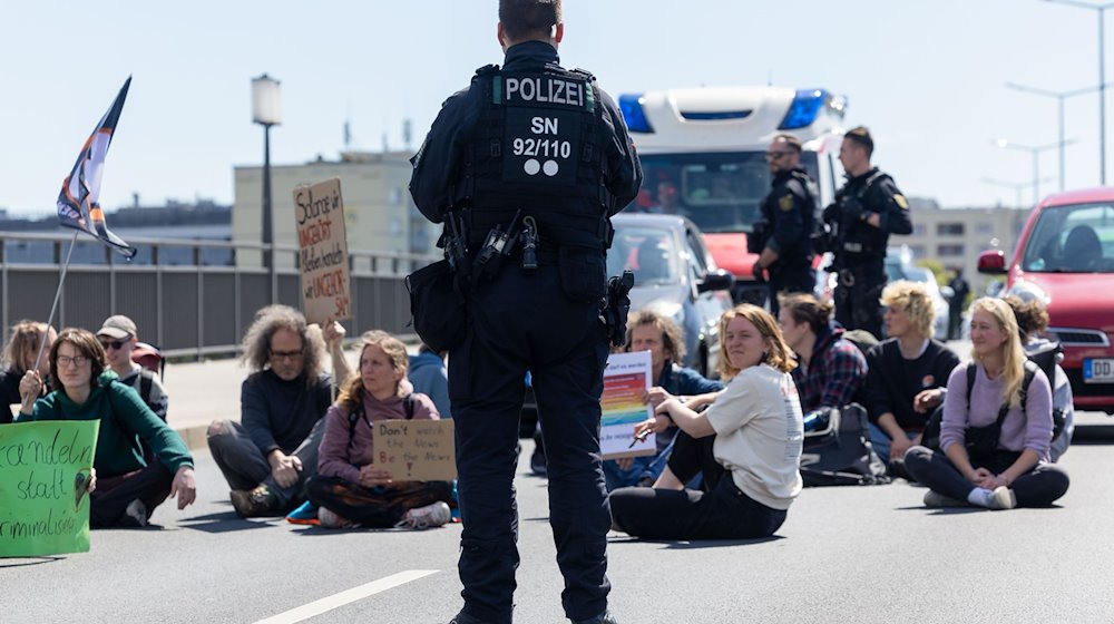A police officer observes climate activists on the Carola Bridge in Dresden / Photo: Daniel Schäfer/dpa